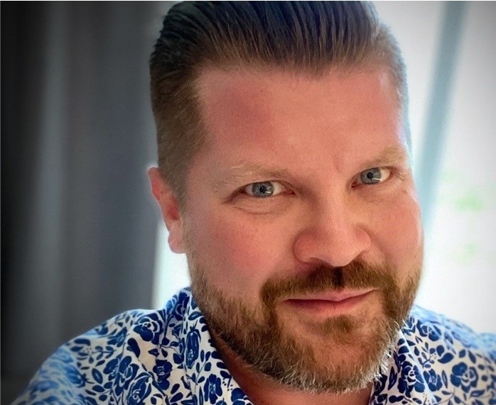 une personne avec une barbe et une moustache portant une chemise bleue et blanche