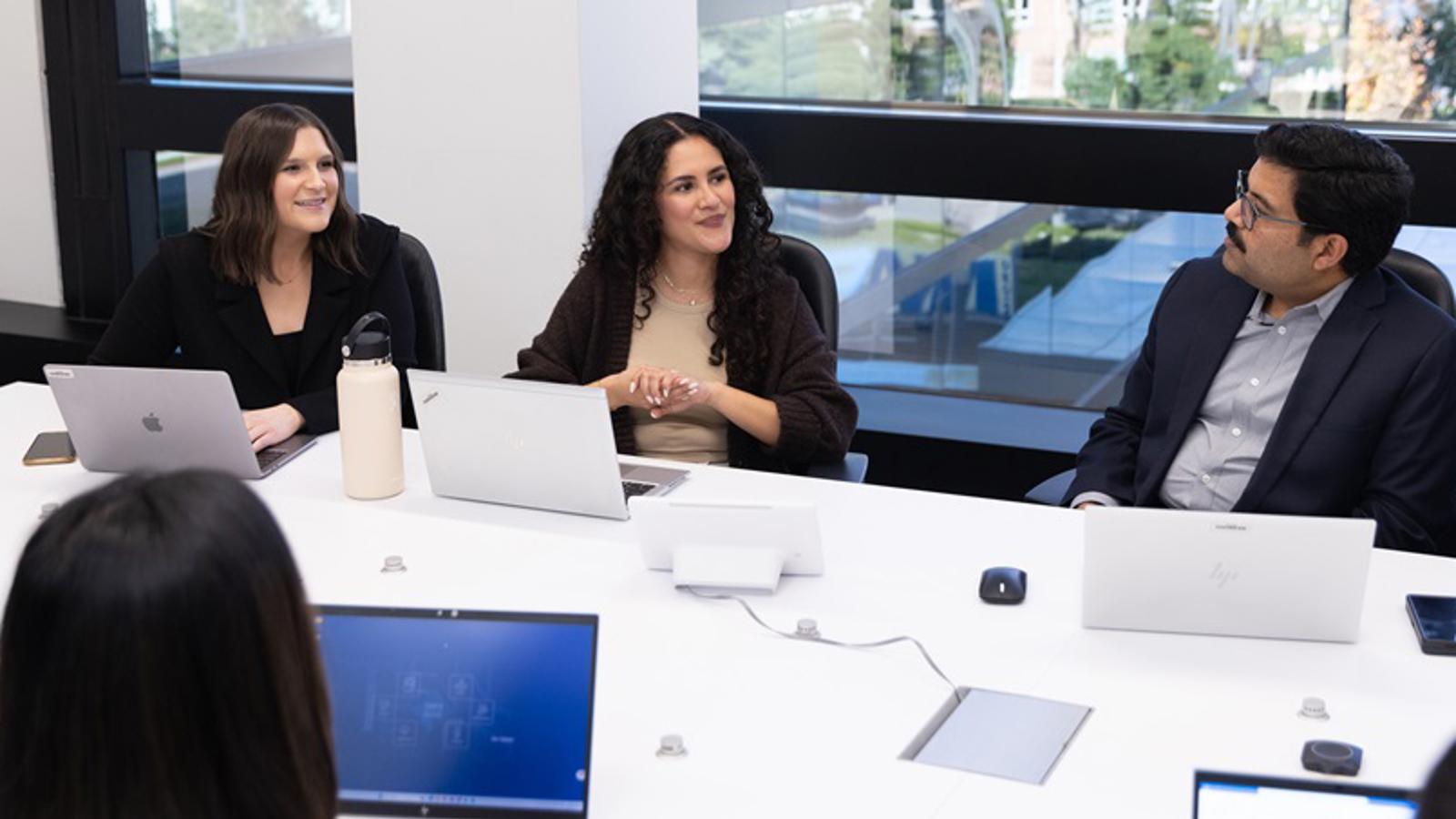 Un grupo de personas sentadas en una mesa con computadoras portátiles