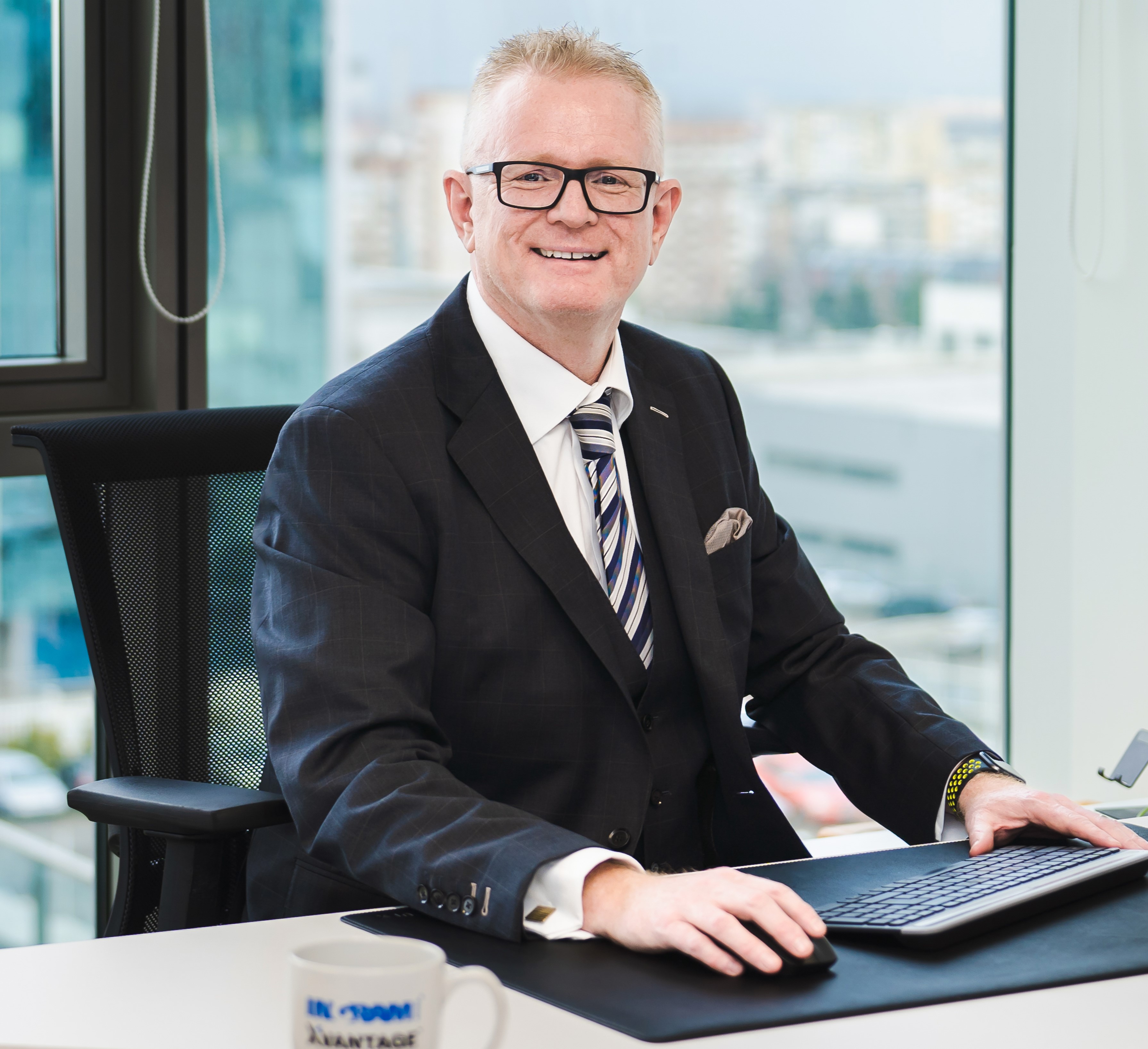 a person in a suit and tie sitting at a desk with a computer