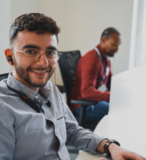 une personne portant des lunettes et un casque d’écoute assise à un bureau