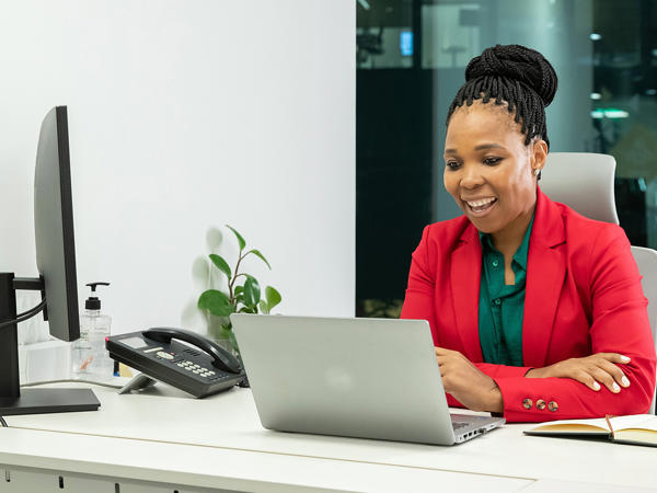 Female Working Behind Laptop In Red Jacket