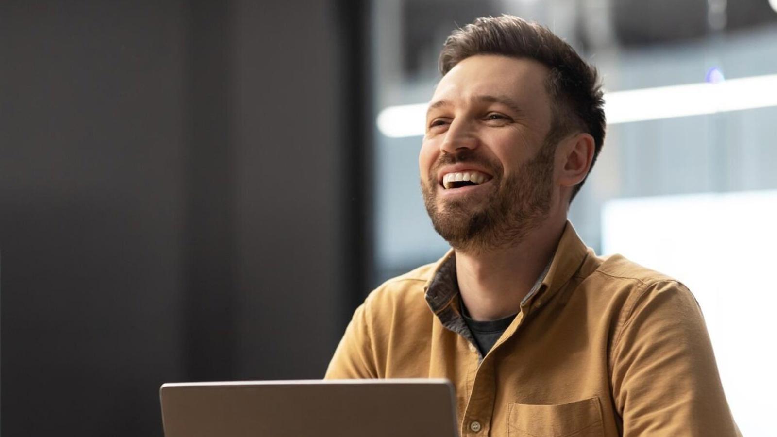 a person smiling at a laptop