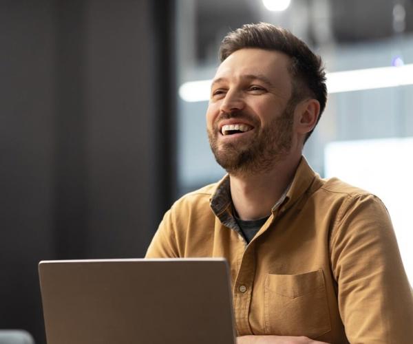 a person smiling at a laptop