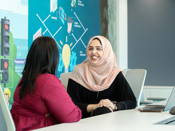 a person wearing a head scarf sitting at a table with another person