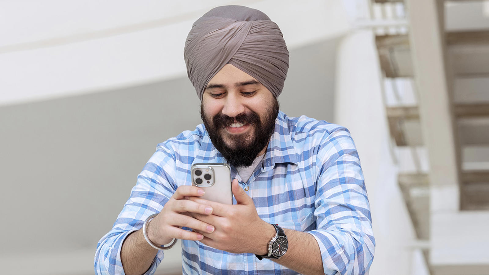a man with a turban on his head looking at his phone