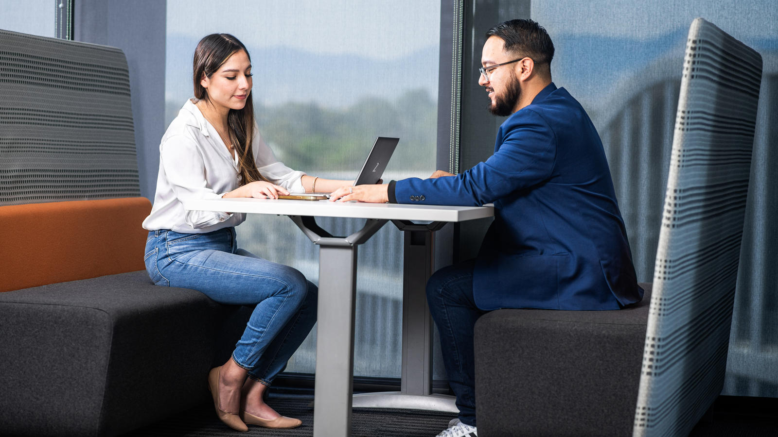 a person and person sitting at a table with a laptop