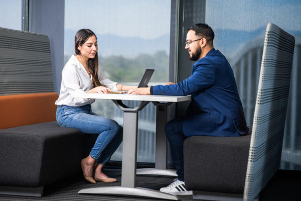 a person and person sitting at a table with a laptop