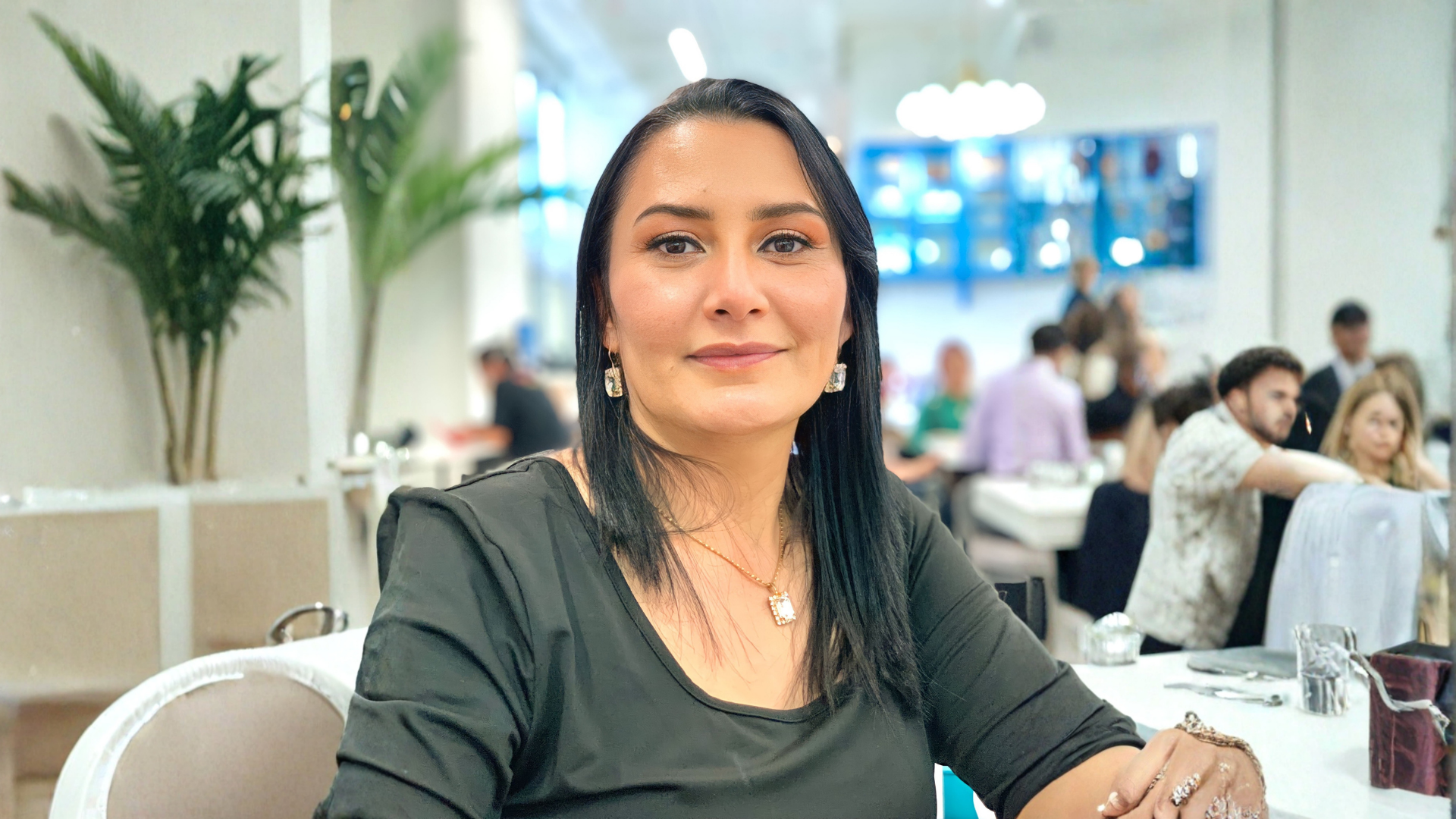 a person with long black hair and gold earrings