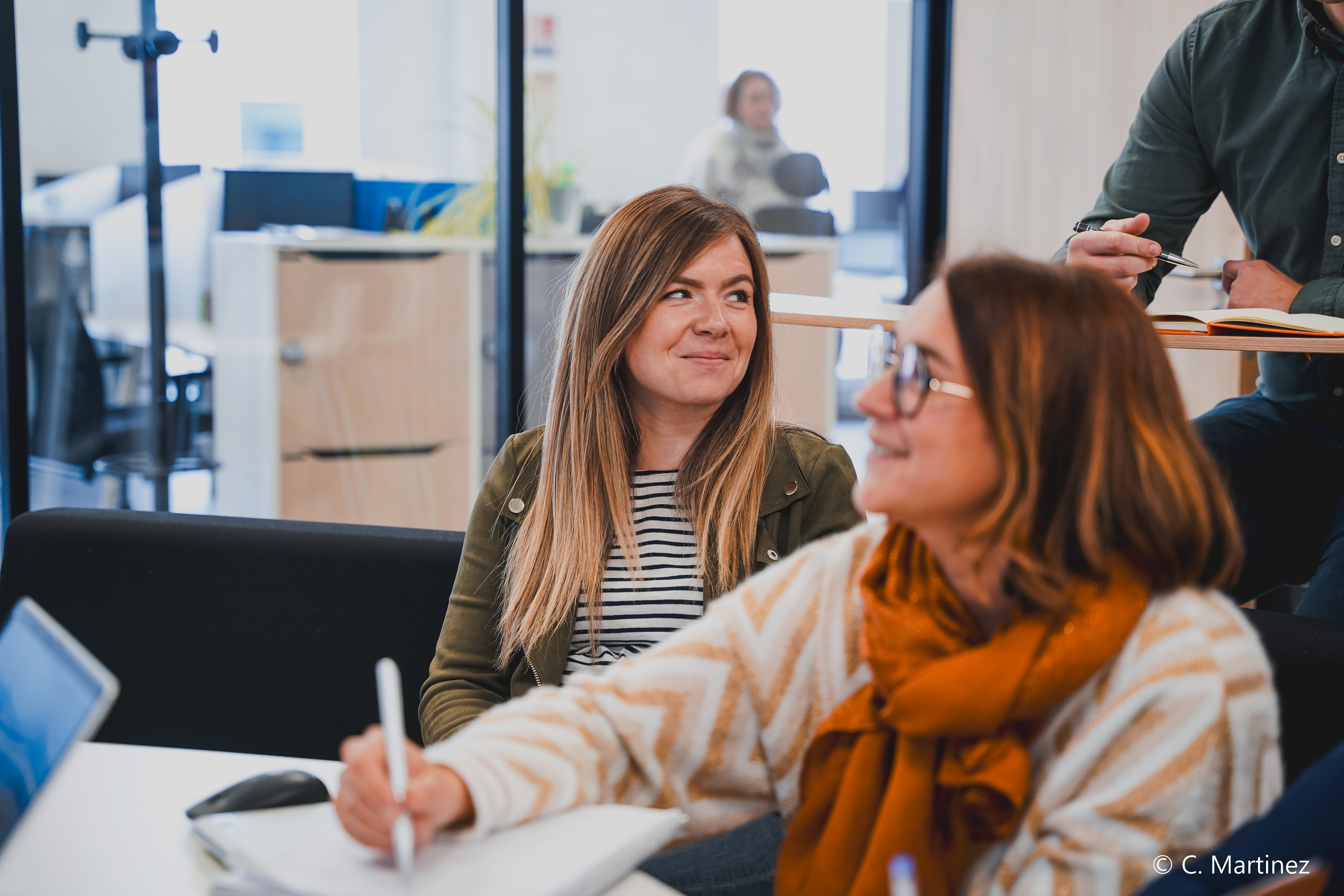 une personne assise à une table avec un stylo à la main