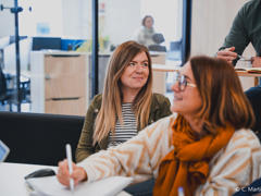une personne assise à une table avec un stylo à la main