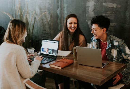 a group of people sitting at a table with laptops