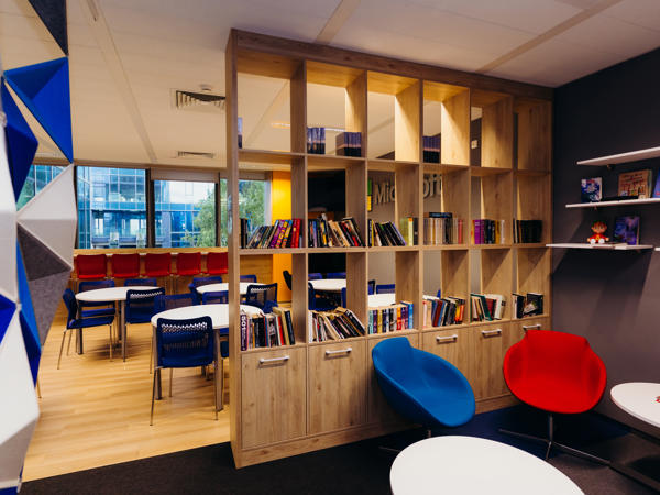a room with a book shelf and chairs