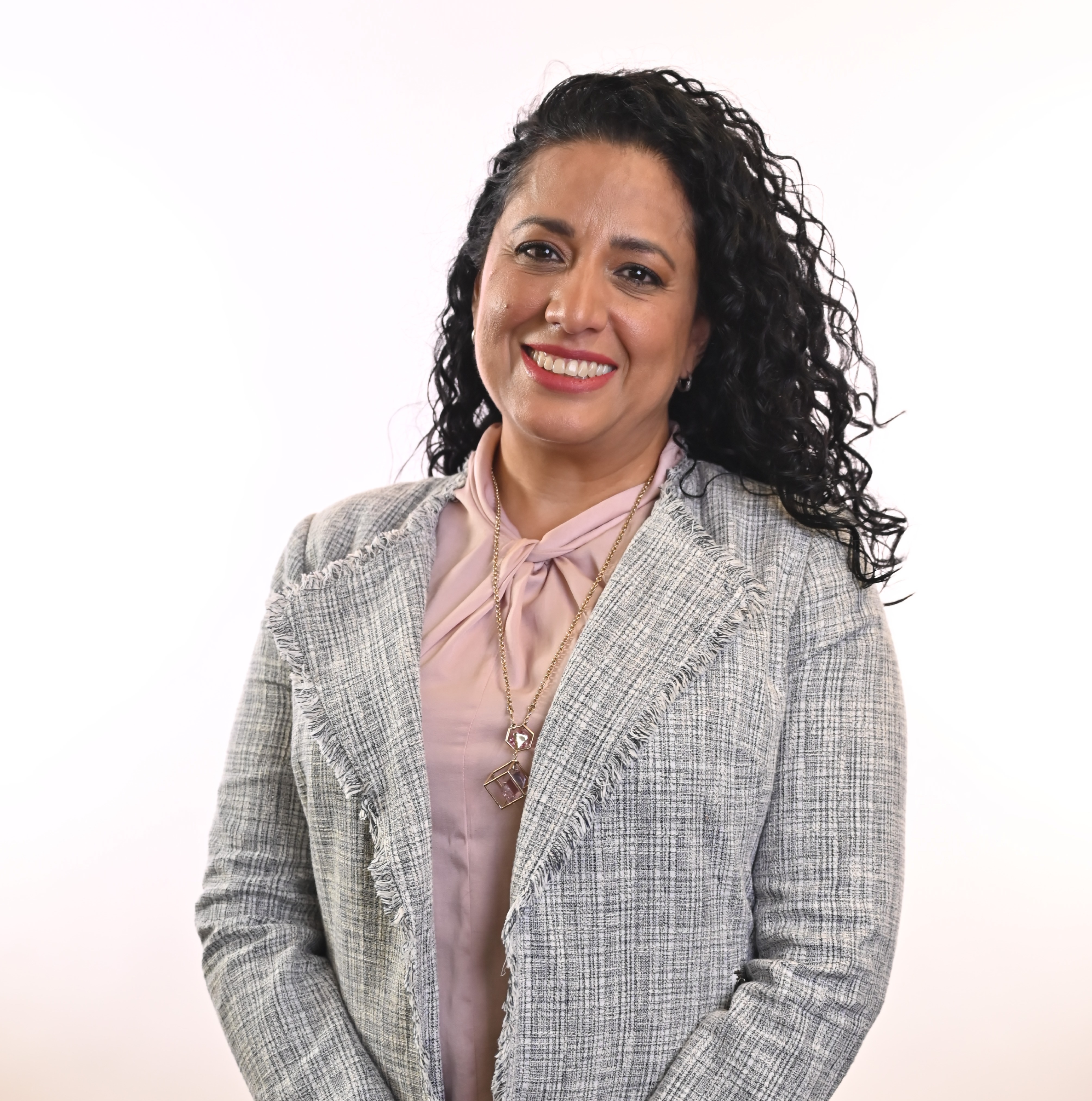 a person with long curly hair wearing a gray jacket and pink shirt