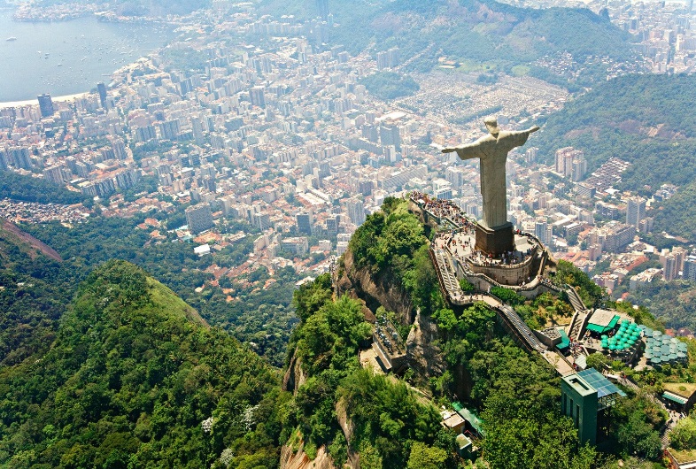 a statue on a mountain with a city in the background