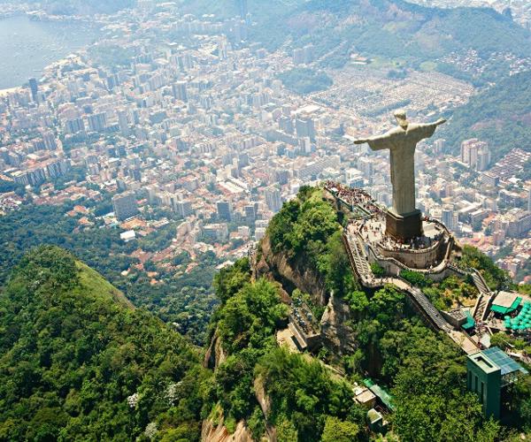 a statue on a mountain with a city in the background