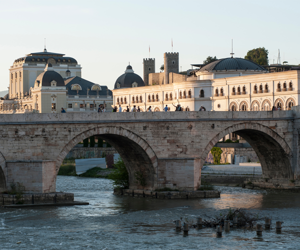 a bridge over a river with a large building in the background