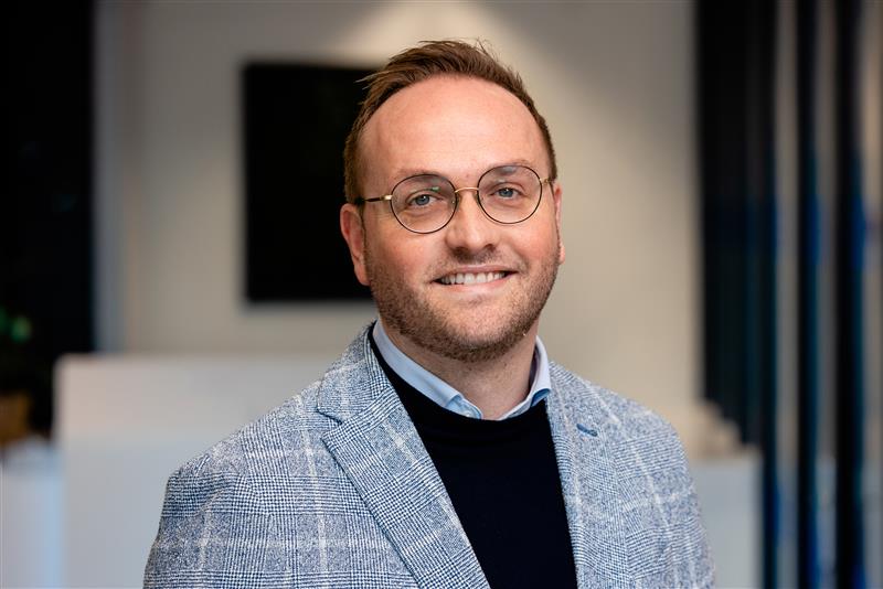a person wearing glasses and a grey jacket