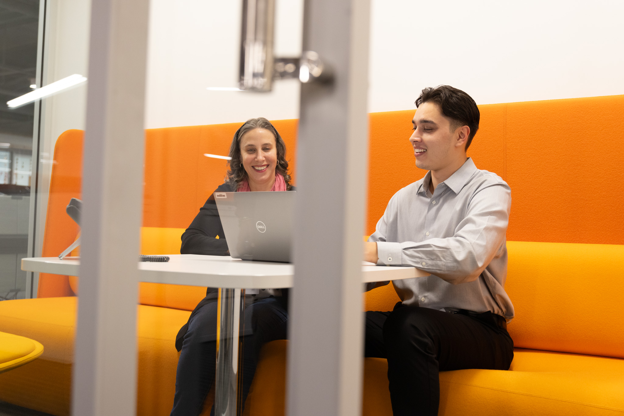 a person and person sitting at a table with a laptop