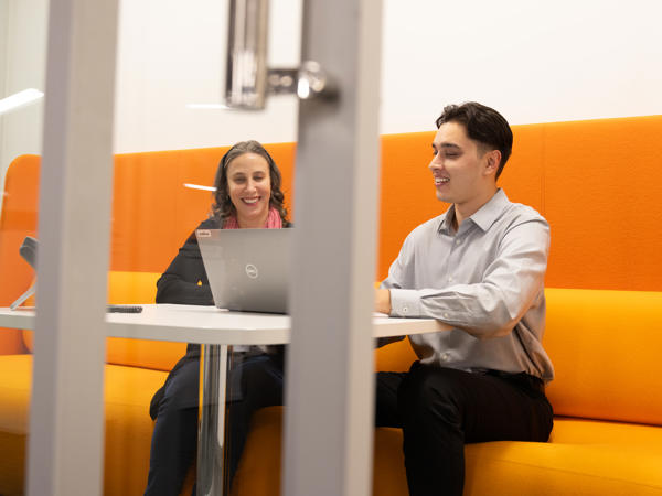 a person and person sitting at a table with a laptop