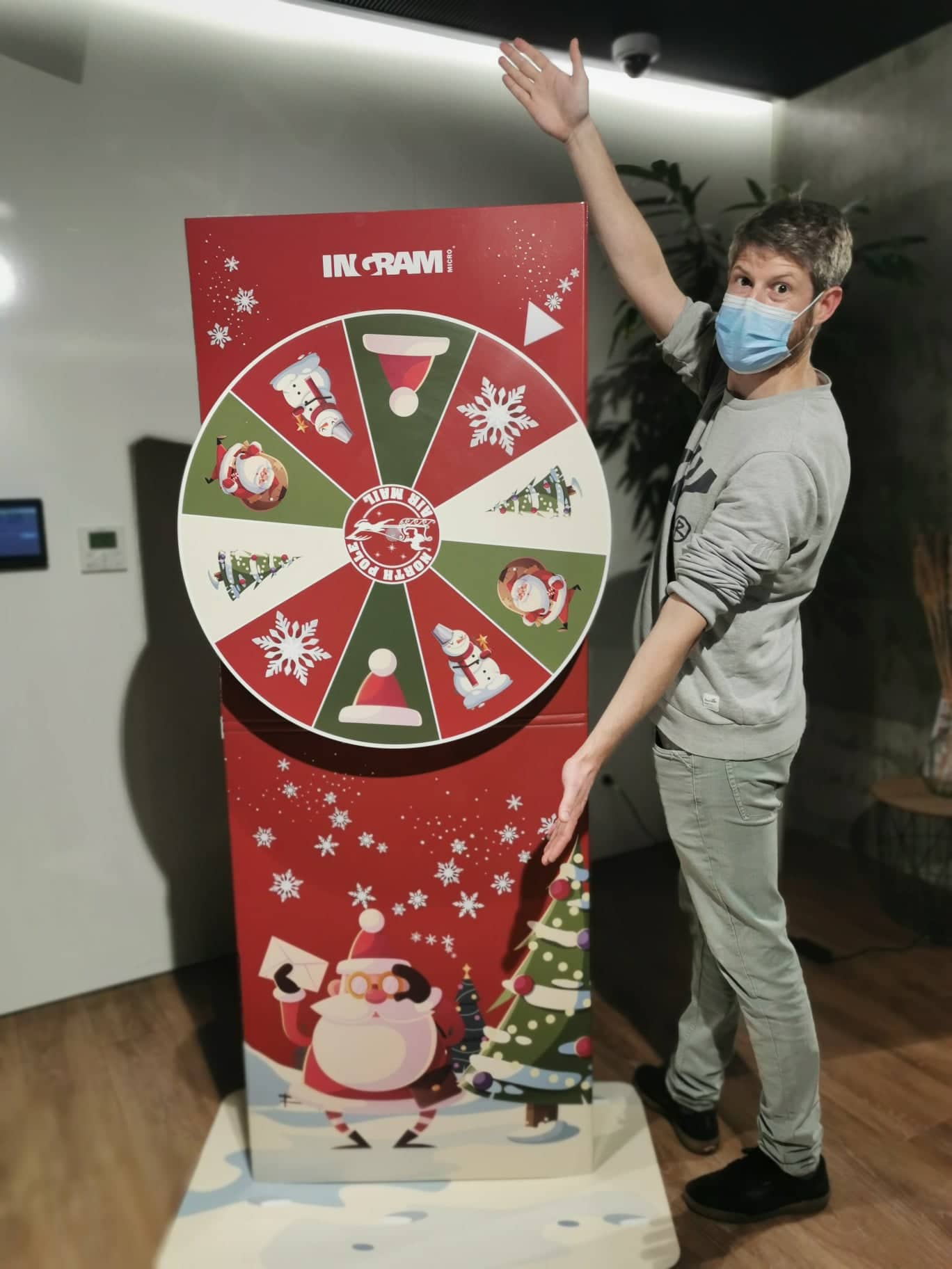Une personne portant un masque facial se tient à côté d’un grand jeu en carton rouge et blanc
