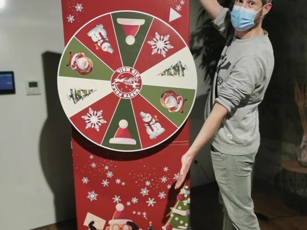 Une personne portant un masque facial se tient à côté d’un grand jeu en carton rouge et blanc