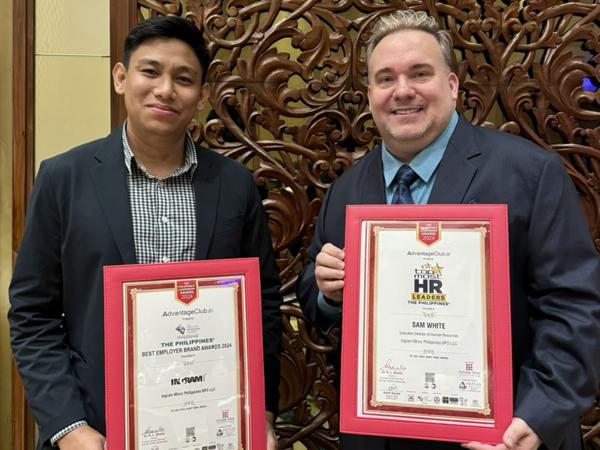 two men holding certificates in front of a carved wood wall