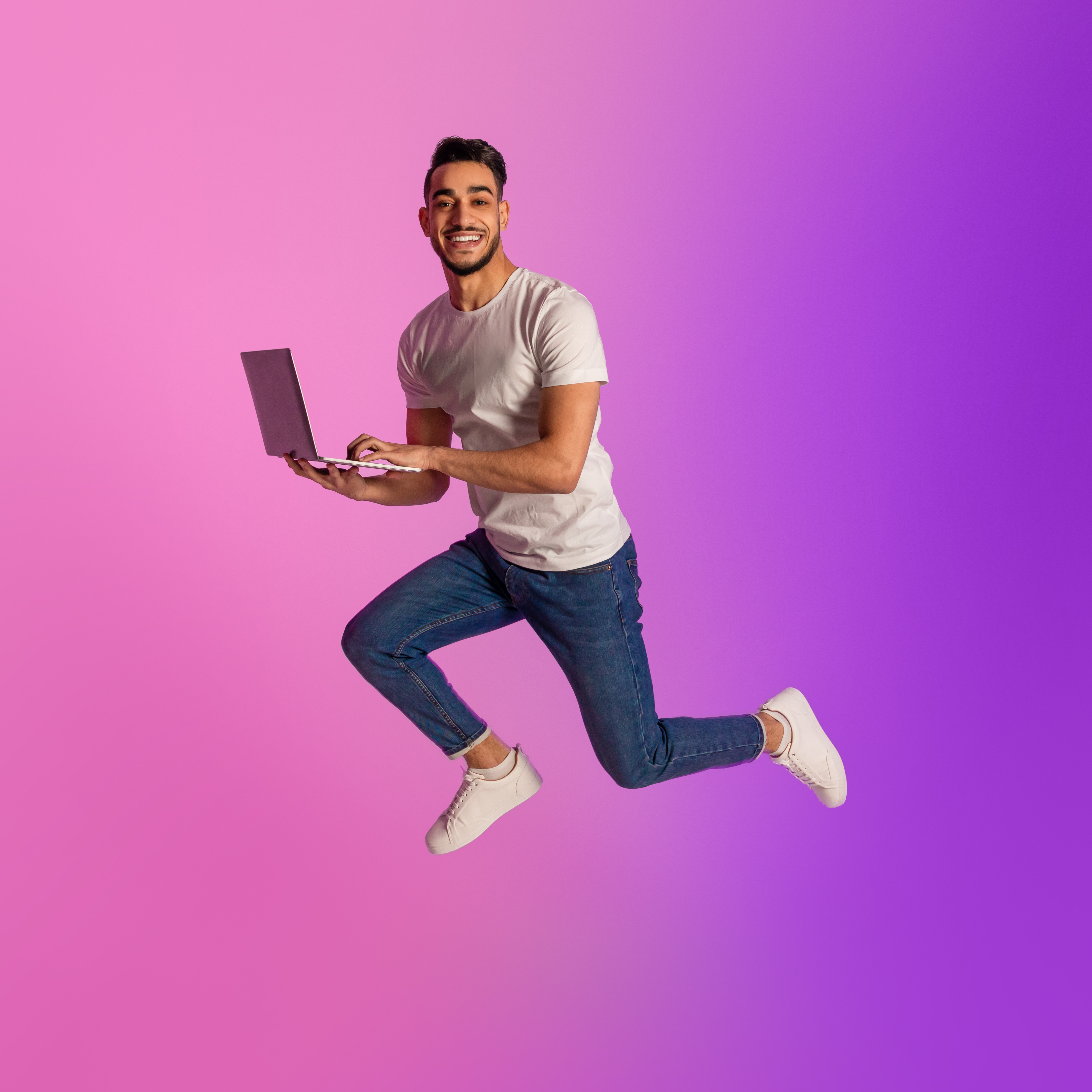 a person jumping in the air holding a laptop