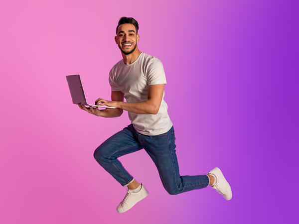 a person jumping in the air holding a laptop
