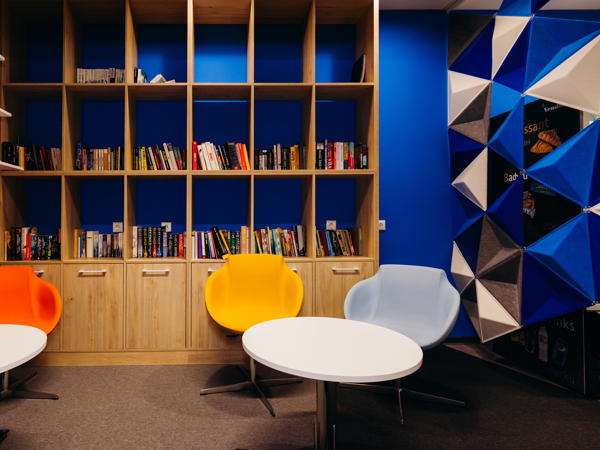 a room with a book shelf and chairs