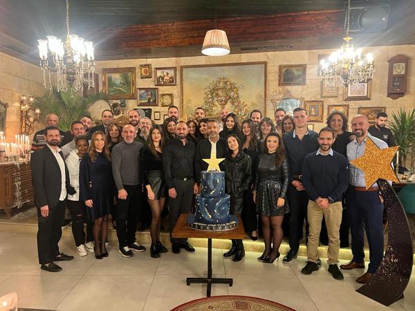 a group of people standing in front of a cake